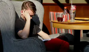 Młody mężczyzna siedzący w fotelu i czytający książkę biznesową, skupiony na lekturze i refleksji nad rozwojem osobistym oraz karierą zawodową